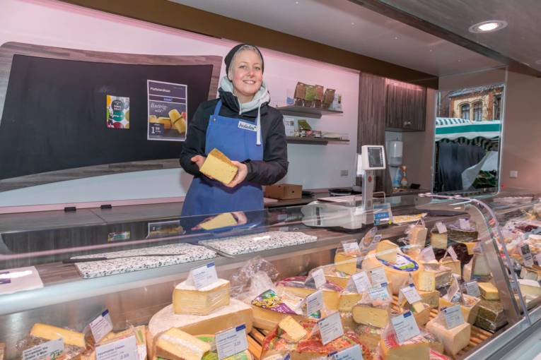 Eine Verk&auml;uferin im K&auml;sestand auf dem Wochenmarkt.